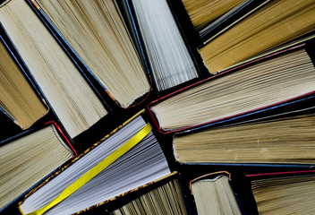 Naklejka premium Lots of colourful thick open books stand on a dark background