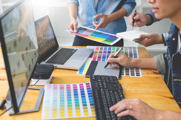 graphic designer team working on web design using color swatches editing artwork using tablet and a...