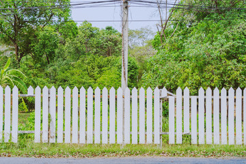 Old white wooden fence with a broken board at the roadside area