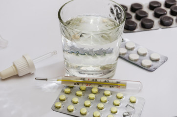 pills and a glass of water on a white background