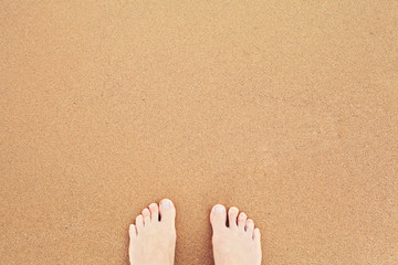 Top view of feet on sea sand. Vacation on ocean beach and summer holiday concept