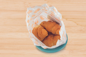 Home made fresh croissant in bag on background.