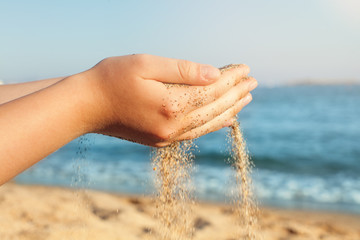 Girl relaxing on sea beach. Sand falling from the female hands on sea beach background