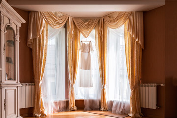 Wedding dress hanging in the living room on the window