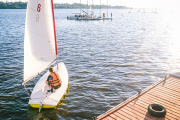 Sailing. The athlete on the yacht sails from the coast. An active form of water sports....