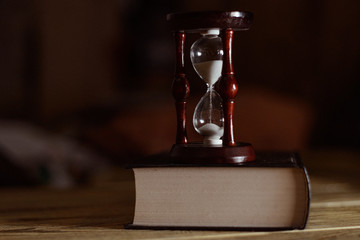 Hourglass on the book. The concept of time and reading.