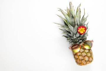 Summer mood concept. Tropical background with ripe organic pinapple with leafy crown looking like a face wearing hipster mirrored sunglasses. Flat lay, top view, copy space, isolated.