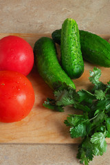 Vegetable for village salad.  Cucumbers, tomatoes and parsley on brown  table. 