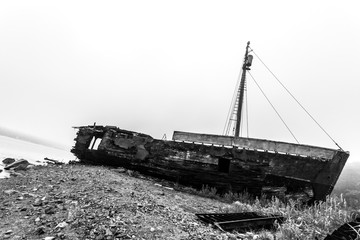 Old wooden wrecked ship in the morning fog. Black and white image