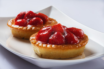 Basket-cakes with mascarpone cheese and decorated with strawberry on white plate. High Key. Close up. Selective focus. 
