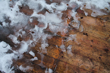 Melting snow on a wooden bridge in early spring
