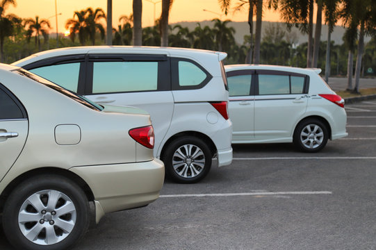 Image of cars parking in outdoor parking lot with sunset sky background in twilight evening of sunny day.