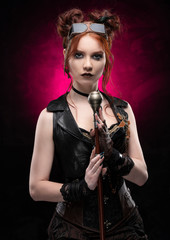 A beautiful red-haired cosplayer girl wearing a Victorian-style steampunk costume with large breasts in a deep neckline and glasses holding a cane on a black and purple background