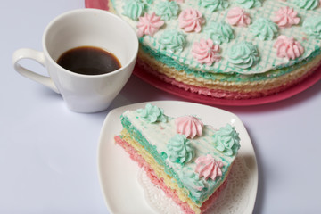 The piece is cut off and lies side by side on a saucer. Nearby is a cup of coffee. Waffle cake made from cream soaked cakes. Decorated with cream flowers.