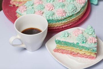 The piece is cut off and lies side by side on a saucer. Nearby is a cup of coffee. Waffle cake made from cream soaked cakes. Decorated with cream flowers.