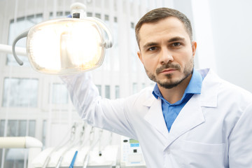 Handsome male professional dentist at his office