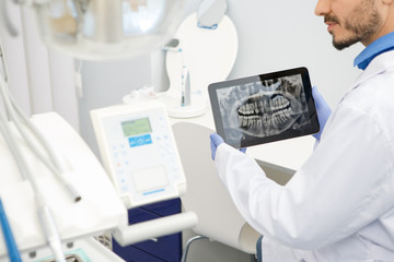 Professional male dentist using a digital tablet at work
