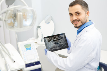 Professional male dentist using a digital tablet at work