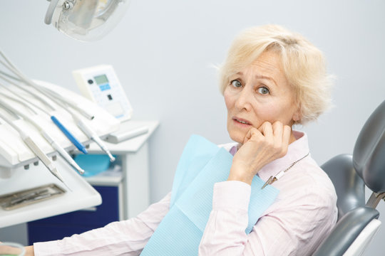Senior woman suffering from toothache visiting dentist