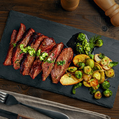 Tasty Pan-Seared Hanger Steak with brussels sprouts, potatoes and onion meal ona  table. Healthy home-made food. Top view above.