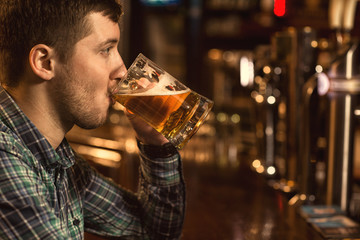 Young man enjoying drinking beer at the pub