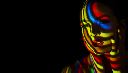 Beautiful young girl with multi-colored stripes on the body from the projector.