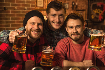 Happy male friends enjoying beer together at the bar