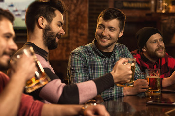 Happy male friends enjoying beer together at the bar