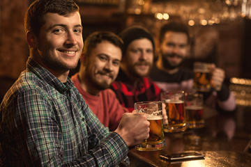 Happy male friends enjoying beer together at the bar