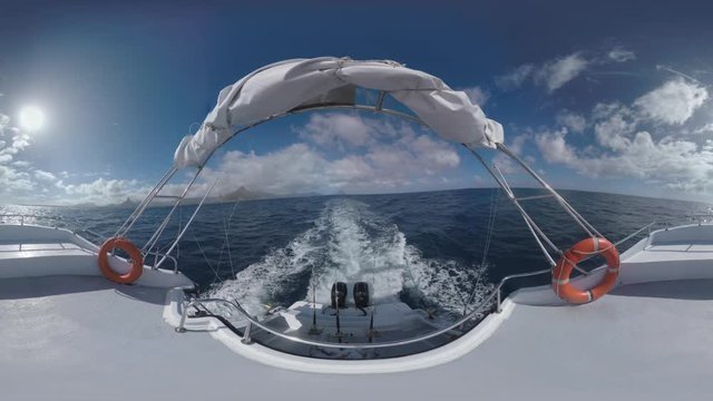 360 VR video. White yacht sailing in the ocean, view to the distant mountains on of Mauritius Island and vast ocean from the upper deck. Fishing-rods fixed at the back of the motor boat