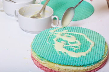A woman lubricates the cakes and puts in a pile. Round wafer cakes of different colors. For making waffle cake. Nearby there is a can of condensed milk to soak the cakes.
