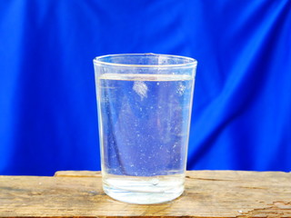 glass of water with ice on blue background