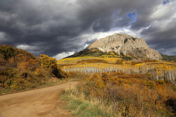 Dirt road in beautiful Colorado mountain landscape under dramatic stormy sky in the Fall