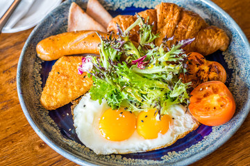 Big breakfast set with chicken ham, jumbo beef sausage, croissant, hashbrown, sunny side up egg, grilled tomato