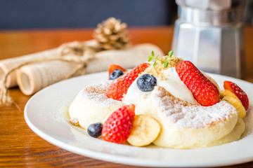 Fruit Salad Souffle Pancake with fresh strawberry, berry, banana, whipped cream and maple syrup