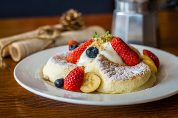Fruit Salad Souffle Pancake with fresh strawberry, berry, banana, whipped cream and maple syrup