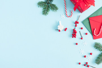 Christmas modern composition. Gifts, fir tree branches, red berries, envelopes, Xmas decorations on pastel blue background. Christmas, New Year, winter concept. Flat lay, top view, copy space