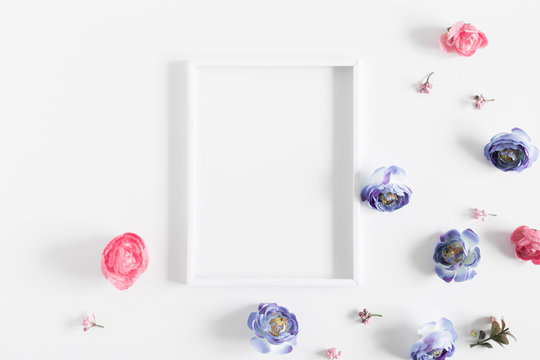 Flowers composition creative. Blank photo frame, pink and light blue flowers on white background. Flat lay, top view, copy space