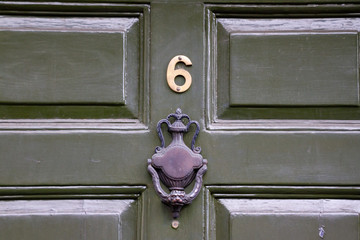 House number six with the 6 in bright meal and a black door knocker