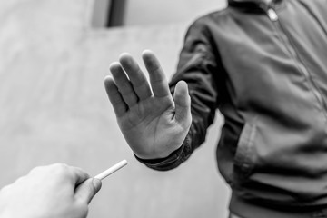 Teenage boy refusing a cigarette, conceptual image of nicotine addiction prevention in black and white.