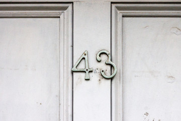 House number 43 with a crooked three as the silver numerals aren't screwed on properly on the white house door