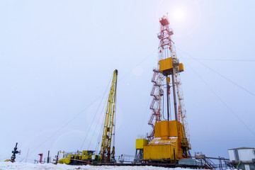 Fototapeta premium Silhouette image of oil and gas drilling rig in the middle of nowhere with dramatic sky. Onshore land rig in oil and gas industry. Land oil drilling rig blue sky