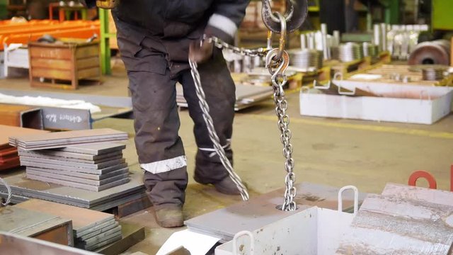 A man pulls out the lifting chain with a hook on the end