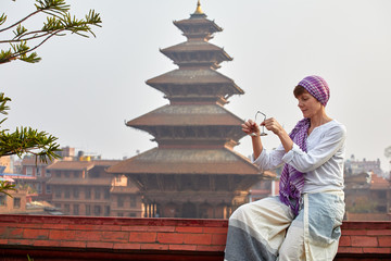 A young woman is meditating with bells on the background of the pagoda. Nepal