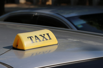 Taxi light sign or cab sign in yellow color with black text on the car roof at the street blurred background