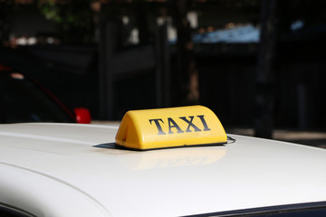 Taxi light sign or cab sign in yellow color with black text on the car roof at the street blurred background