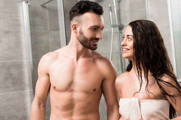 Fototapeta na wymiar cheerful bearded man looking at smiling brunette woman in bathroom