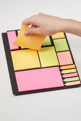 Blank note paper set of different colours forms and sizes. Sticky notes collection on black background. Female hand tear off paper note