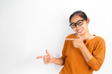 Asian woman wearing orange shirt and eyeglasses isolated on white background smiling and looking at the camera pointing with two hands and fingers to the side.