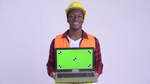 Young happy African man construction worker showing laptop